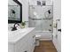 Modern bathroom with wood look floors, vanity sink, and marble tiled tub with glass shower doors at 1837 S East St, Indianapolis, IN 46225