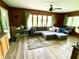 Inviting living room features a large sectional sofa, wood paneling, and ample natural light from the windows at 2221 E 35Th St, Anderson, IN 46013