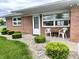 Charming brick home with well-maintained lawn and landscaping with outdoor chairs on the front porch at 2508 Pamela Ct, Anderson, IN 46012