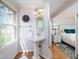 Bright bathroom vanity with a pedestal sink, mirror, and window, adjacent to a comfortable bedroom at 2929 E 62Nd St, Indianapolis, IN 46220
