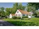 View of the white home showing the exterior, attached garage, landscaped yard, and surrounding trees at 2929 E 62Nd St, Indianapolis, IN 46220