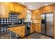 A kitchen with wooden cabinets, black and white tile backsplash, stainless steel appliances and black countertops at 2929 E 62Nd St, Indianapolis, IN 46220
