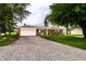 Ranch-style brick home with an attached garage and gravel driveway surrounded by mature trees at 2965 E 1100 N, Pendleton, IN 46064