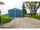 A well-maintained blue storage shed with a gravel driveway and brick border in the backyard at 2965 E 1100 N, Pendleton, IN 46064