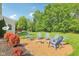 Landscaped backyard featuring a fire pit surrounded by blue Adirondack chairs, perfect for outdoor entertaining at 3267 Cimmaron Ash Ct, Zionsville, IN 46077