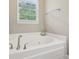 Relaxing white bathtub under a window, complemented by modern fixtures and natural lighting at 3267 Cimmaron Ash Ct, Zionsville, IN 46077