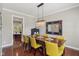 A dining room featuring a chandelier, a dark wood table with yellow upholstered chairs, and hardwood flooring at 3267 Cimmaron Ash Ct, Zionsville, IN 46077