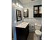 Bathroom featuring light blue walls, dark vanity, a mirror and cabinet for storage at 3645 Winings Ave, Indianapolis, IN 46221