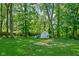 Serene backyard featuring a storage shed, fire pit, and mature trees, creating a private and relaxing outdoor space at 38 Hawthorne Ct, Carmel, IN 46033