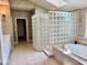 A bathroom featuring a glass block shower wall and a large soaking tub with tile surround at 5200 W Shoreline Ter, Muncie, IN 47304