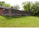 Brick house backyard featuring a tall concrete wall, fresh green grass, and plenty of shrubbery at 706 Bobs Ct, Beech Grove, IN 46107