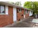 Brick house exterior with a concrete patio, multiple entryways, and white window shutters at 706 Bobs Ct, Beech Grove, IN 46107