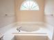Well-lit bathroom features a garden tub with tile surround and an arched window for natural light at 9127 Pointe Ct, Fishers, IN 46037