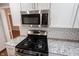 Close up of the stainless steel gas stove with stainless microwave and granite counters with subway tile backsplash at 9127 Pointe Ct, Fishers, IN 46037
