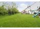 Large, well-manicured backyard featuring a trampoline, playset, and mature trees with a deck off the house at 10144 Water Crest Dr, Fishers, IN 46038