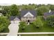 A beautiful two-story brick home with a well-maintained lawn, mature trees, and attached garage from above at 10144 Water Crest Dr, Fishers, IN 46038