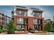 Beautiful three-story townhome featuring brick facade, large windows, and manicured landscaping with comfortable outdoor seating at 11940 Citywalk Dr, Fishers, IN 46038