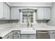 Close-up of a kitchen featuring a farmhouse sink, bright countertops, and stainless steel dishwasher at 12388 Camberley Ln, Carmel, IN 46033
