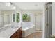 Bathroom with large tub, glass shower, and tiled floor, illuminated by natural light at 12409 Dellfield W Blvd, Carmel, IN 46033