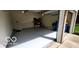 View of an attached garage, showing the epoxy floor, storage shelf, and open door to the driveway at 12409 Dellfield W Blvd, Carmel, IN 46033