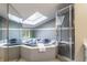 Bathroom with a jacuzzi tub under a skylight and glass enclosed shower with window view at 12469 Springmill Rd, Carmel, IN 46032