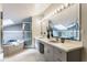 Bathroom with double sinks, large mirror, walk in shower, and relaxing jacuzzi tub under a skylight at 12469 Springmill Rd, Carmel, IN 46032