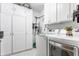 Bright laundry room with modern washer and dryer, white cabinets, and sink at 12469 Springmill Rd, Carmel, IN 46032