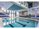 Indoor pool area features a bright blue pool, modern staircase, and a decorative tiled accent wall at 12469 Springmill Rd, Carmel, IN 46032