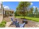 Inviting backyard patio with brick pavers, blue Adirondack chairs, and a screened-in porch overlooking the lush green lawn at 14094 Pecos Ct, Carmel, IN 46033