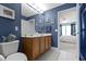 A bathroom with double vanity sinks, framed art, blue walls, and neutral tile flooring at 14094 Pecos Ct, Carmel, IN 46033