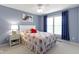 Blue bedroom with a ceiling fan, a window with curtains, and a large bed with floral bedding at 14094 Pecos Ct, Carmel, IN 46033