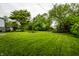 Lush backyard space showing mature trees, a fire pit, and green grass. A perfect place to enjoy the outdoors at 1431 N Bolton Ave, Indianapolis, IN 46219