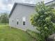Exterior view of home featuring gray siding, well-maintained lawn, and landscaped garden bed at 160 Rambling Rd, Greenfield, IN 46140