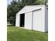 A large white storage building with sliding doors stands on a lush green lawn next to trees at 21749 Oak Ridge Rd, Sheridan, IN 46069