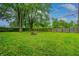Large, grassy backyard with a wooden fence and mature trees, offering privacy and a serene outdoor space at 2228 Dover St, Anderson, IN 46013
