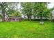 Expansive backyard with mature trees, lush green lawn, and a small outdoor prep table, perfect for gatherings at 2228 Dover St, Anderson, IN 46013