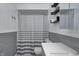 Bathroom featuring a shower with striped curtain, gray tiled walls, and contemporary shelving at 2228 Dover St, Anderson, IN 46013