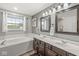 Primary bathroom with double vanity, large soaking tub, and stylish light fixtures at 2802 Singletree Dr, Indianapolis, IN 46234