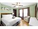 Bright bedroom with hardwood floors, ceiling fan, queen bed, and sitting area with armchair at 344 N Whittier Pl, Indianapolis, IN 46219