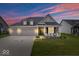 Single-Gathering home at dusk, featuring a three-car garage and a welcoming front porch with comfortable seating at 3463 Sunnyvale Dr, Brownsburg, IN 46112