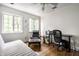 Bright bedroom features hardwood floors, two windows, ceiling fan, and black desk and chair at 4410 N Pennsylvania St, Indianapolis, IN 46205