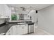 Well-lit kitchen with white cabinets, stainless steel dishwasher, and a view of the open-concept living space at 4907 Franklin Villas Pl, Indianapolis, IN 46237