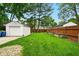 Spacious backyard with a detached garage, wooden fence, and lush green lawn at 6176 Kingsley Dr, Indianapolis, IN 46220