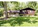 A charming exterior of a home with stone and wood siding, surrounded by lush greenery and mature trees at 6248 Graham Rd, Indianapolis, IN 46220