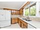 Kitchen featuring wood cabinets, double sink, white appliances, and a view of the backyard at 6248 Graham Rd, Indianapolis, IN 46220