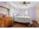 Serene bedroom featuring light purple walls, hardwood floors, a comfortable bed, and a bright window view at 671 W 350 N, Shelbyville, IN 46176