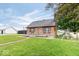 Charming single-story home featuring orange siding, a stone chimney, and a spacious front lawn with a playground at 671 W 350 N, Shelbyville, IN 46176