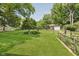 A large backyard with a manicured lawn, privacy fence, and mature trees at 7135 Huntington Rd, Indianapolis, IN 46240