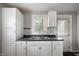 A functional kitchen with white cabinets, neutral walls, a sink with an adjacent door to the backyard at 732 S Biltmore Ave, Indianapolis, IN 46241