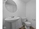 Simple half-bath with pedestal sink, round mirror and wood-look floors at 7323 Waylon Way, Indianapolis, IN 46239